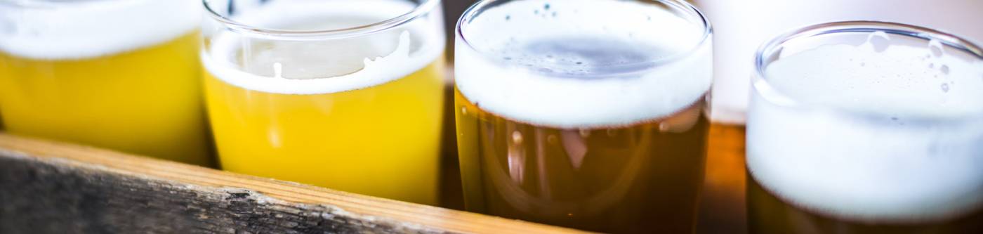 row of four craft beers from light to dark in wooden holder